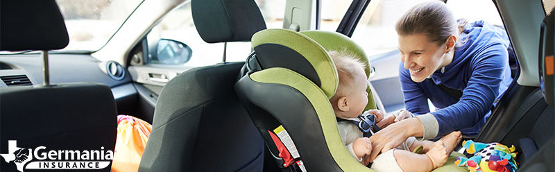 Mother placing child in child safety seat