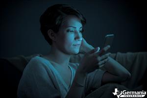 A woman bathed in blue light from her phone