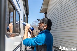 A man caulking windows, performing essential RV maintenance