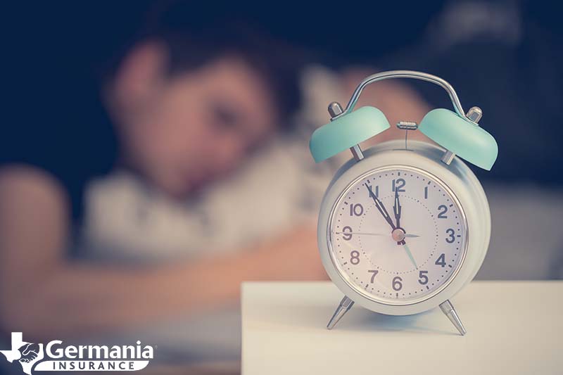 A man laying behind a clock as he adjusts to the end of daylight savings time