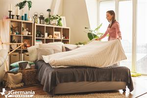 A woman making a bed, preparing her home for Airbnb guests