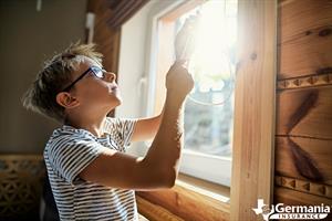 A boy drawing the blinds closed to prevent UV damage. 