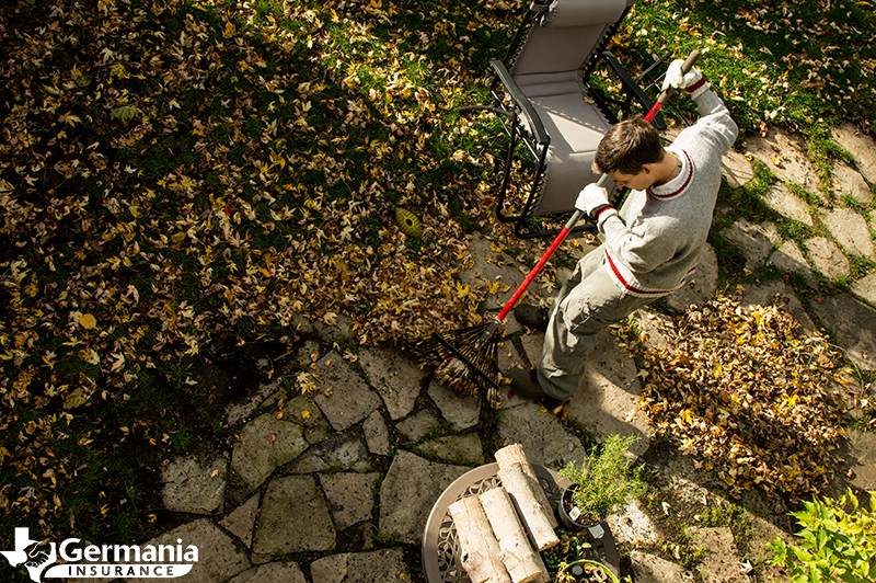 A man raking fall leaves as part of a fall home maintenance checklist